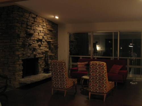 Upper living area (front half) at night with triple slider to catwalk and stacked stone wall with fireplace