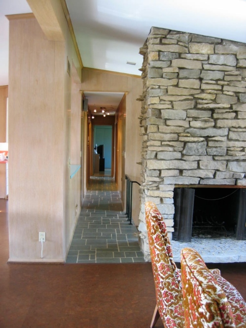 View from living area down main hallway to back bedroom; fireplace in stacked stone wall